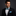 Man wearing a black suit with a blue bow tie and pocket square on a dark background