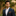 Man in a dark suit with a colorful pocket square against a blurred natural background