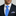 Man wearing a navy suit with a blue checkered tie and accenting pocket square.
