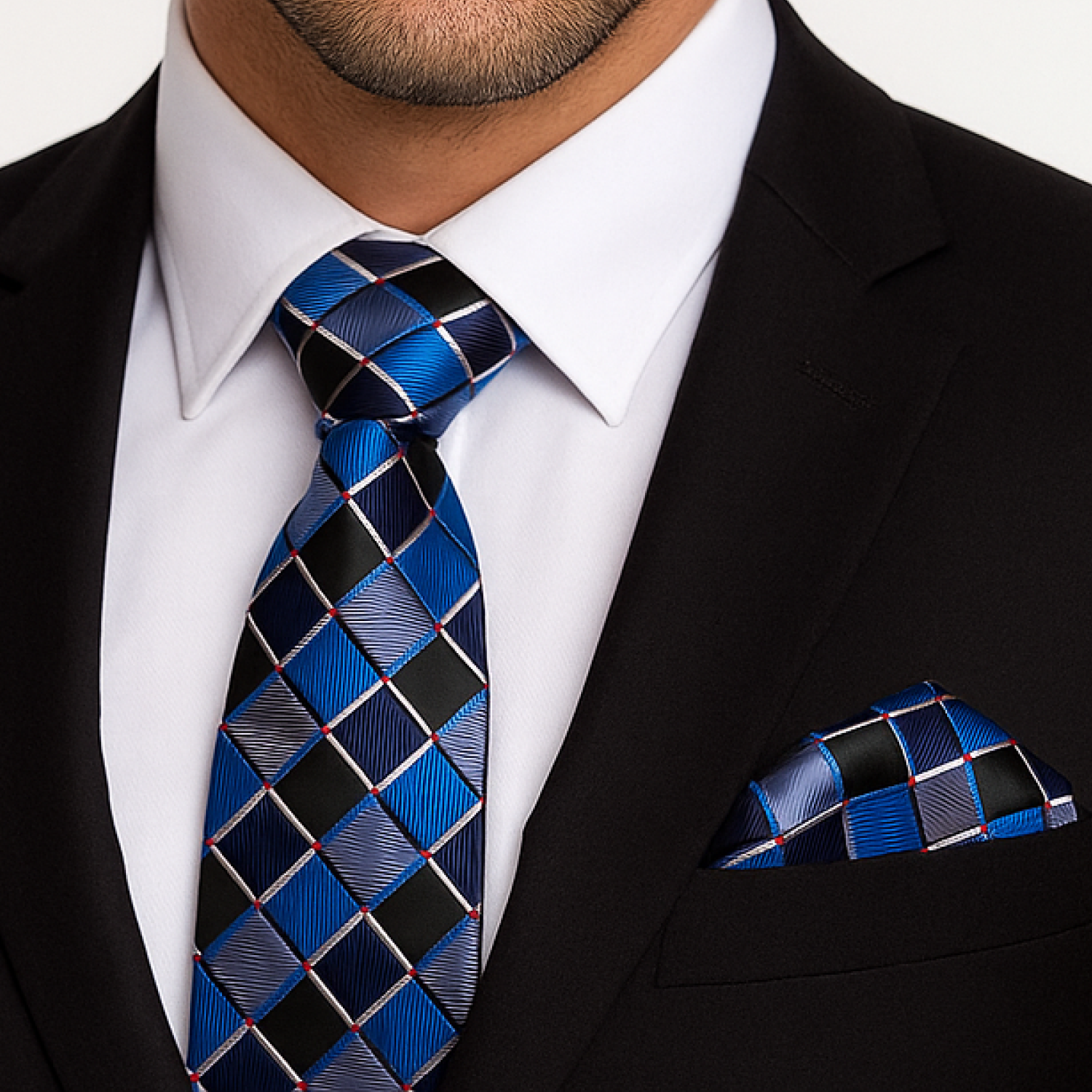 Man wearing a black suit with a blue and black checkered tie and pocket square.