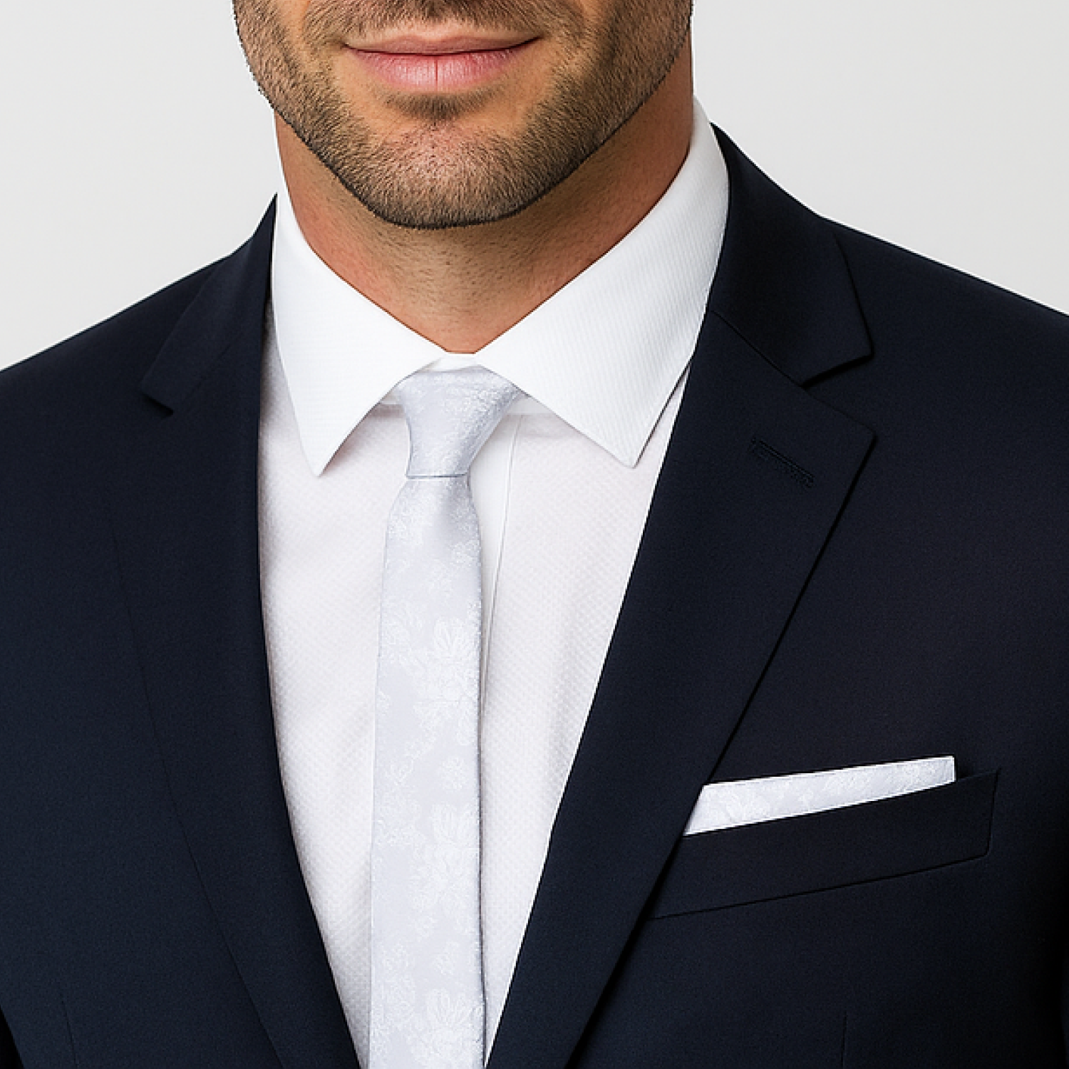 Man wearing a dark suit with a white shirt and tie against a light gray background