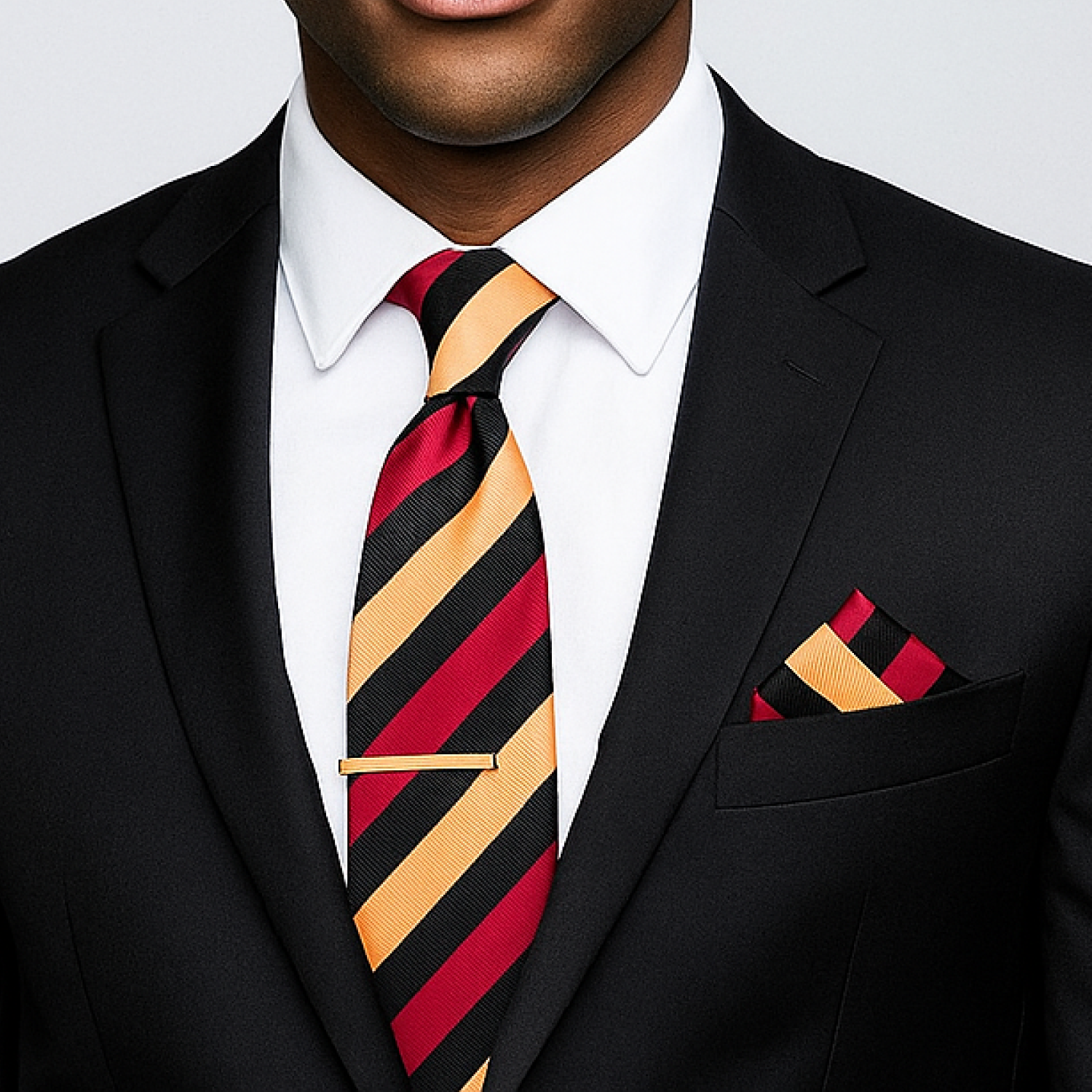 Man wearing a black suit with a red and gold striped tie and matching pocket square.