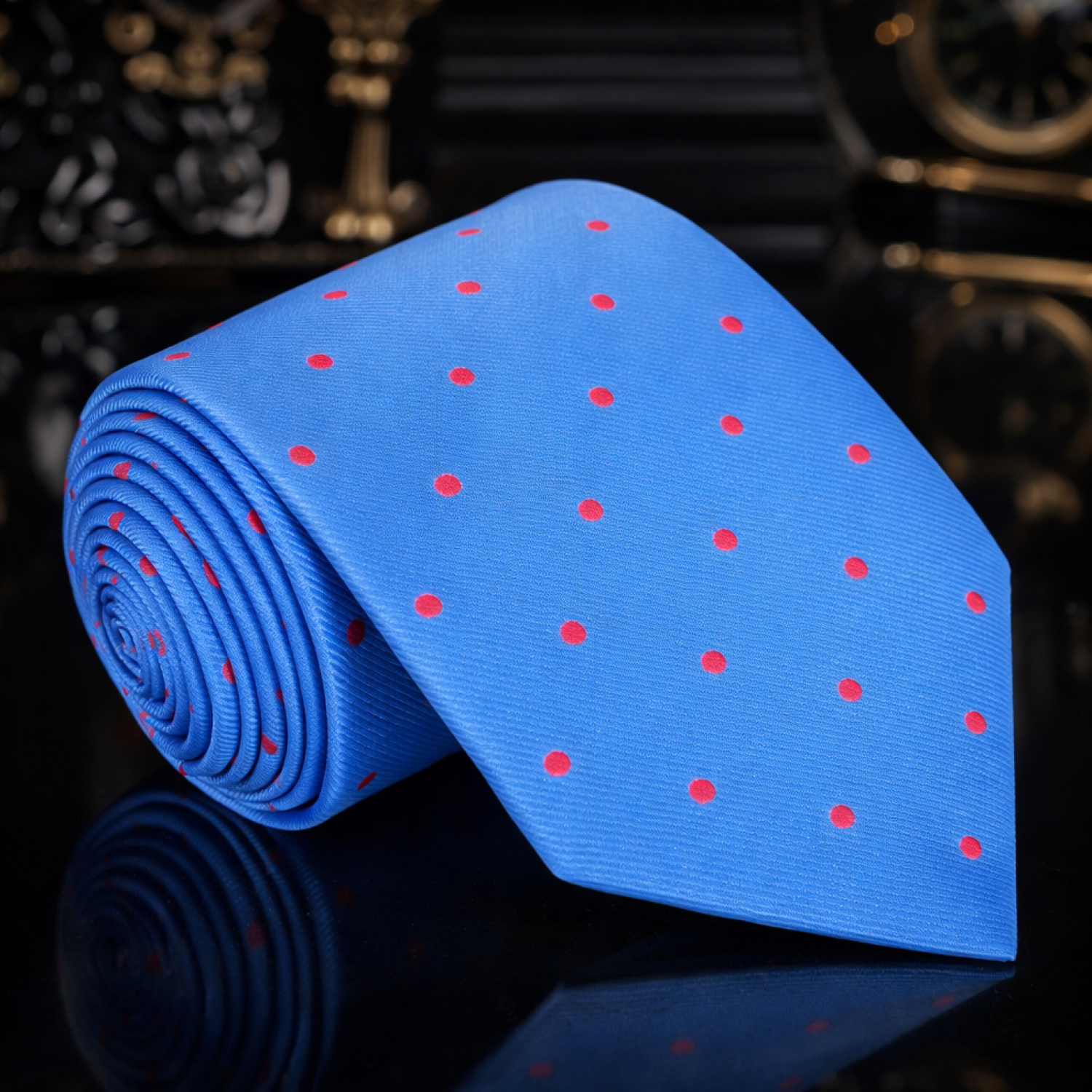 Blue tie with red polka dots on a reflective surface with a dark background