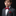 Young boy in a gray suit with a red bow tie and pocket square on a black background