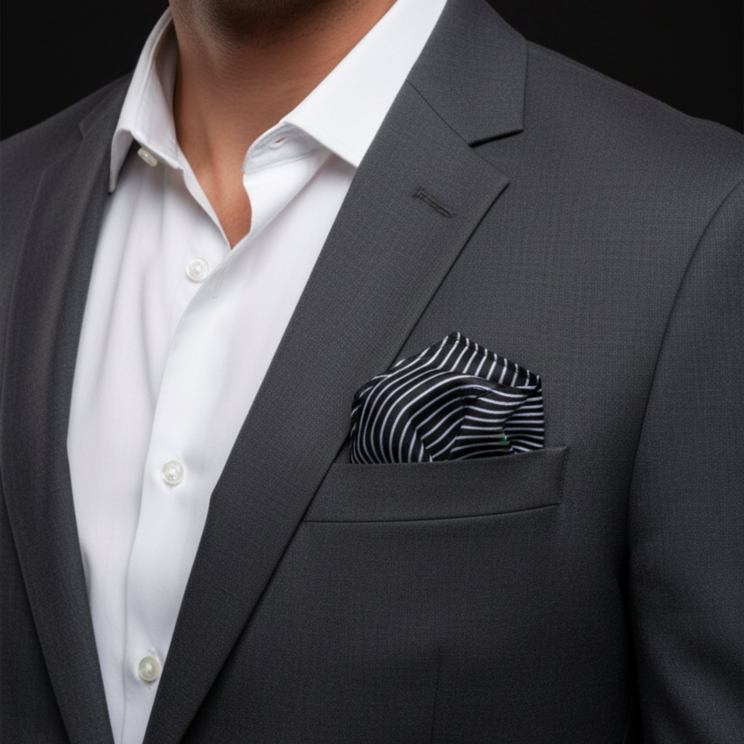 Gray suit jacket with a white shirt and striped pocket square on a black background