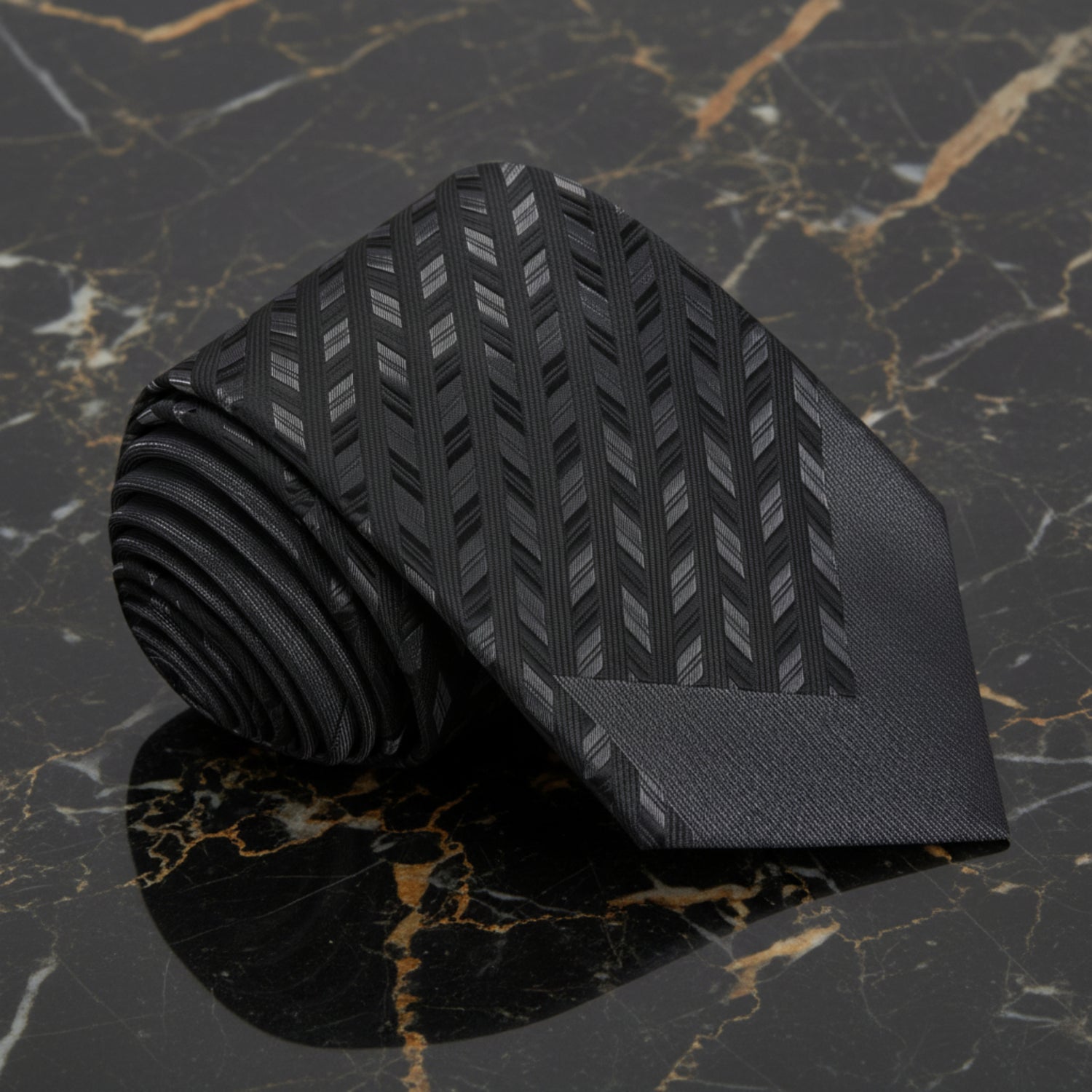 Black patterned tie on a marble surface with suits in the background
