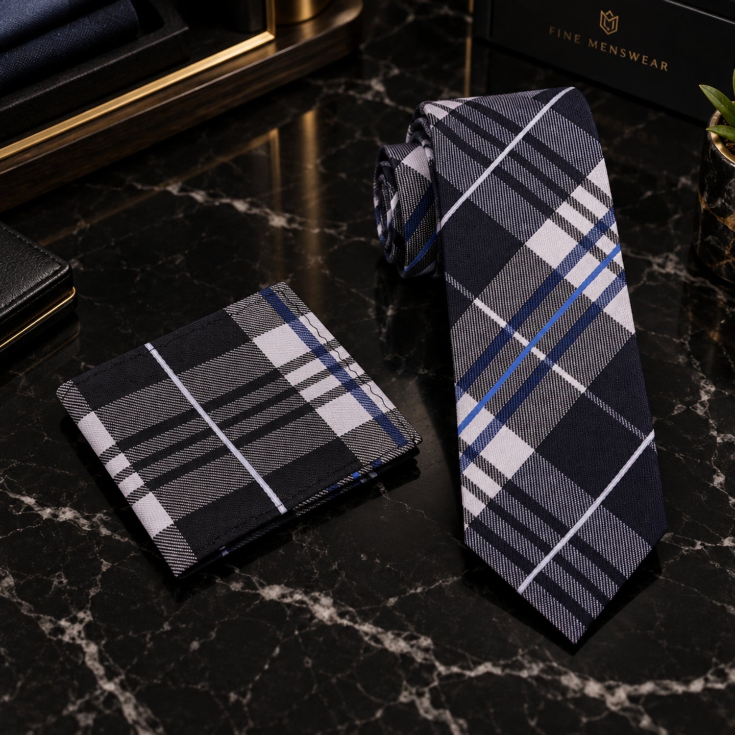 A men's necktie and matching pocket square set in a black, gray, white, and blue plaid pattern, displayed on a clean white background.
