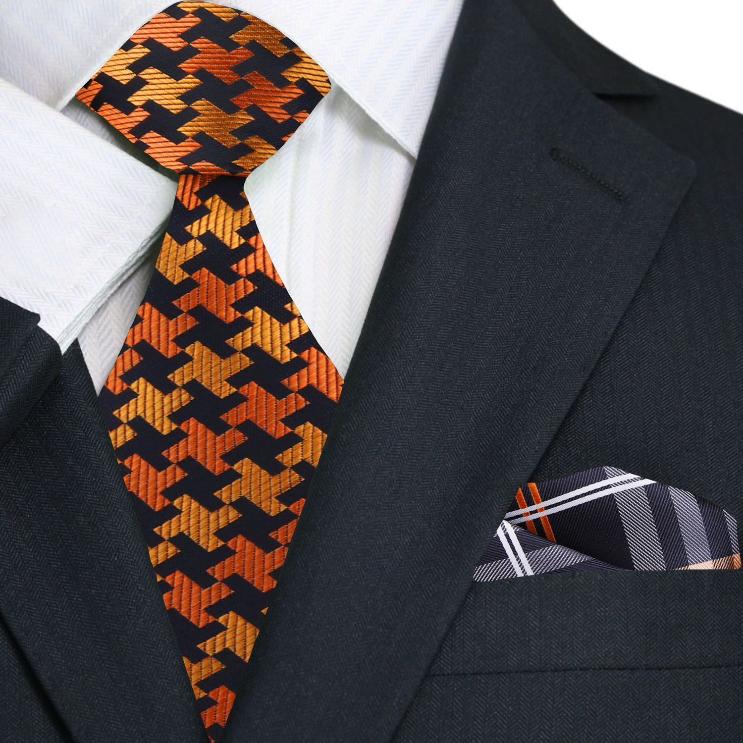 Black suit with orange and black patterned tie and plaid pocket square.