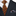 Black suit with orange and black patterned tie and plaid pocket square.