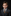 Young boy in a formal suit with a patterned tie against a black background