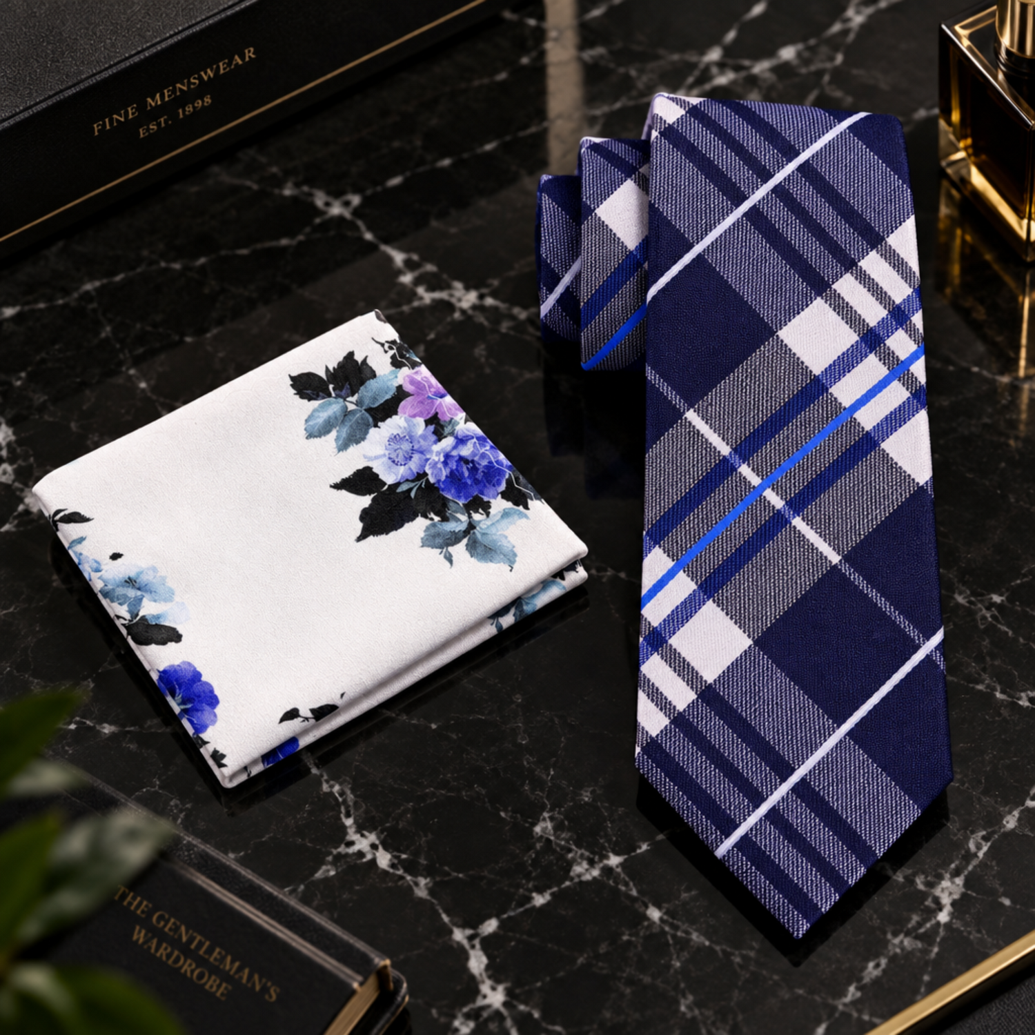 A men's necktie and pocket square set on a white background. The necktie features a navy blue, gray, and white plaid pattern with thin blue accent stripes.
