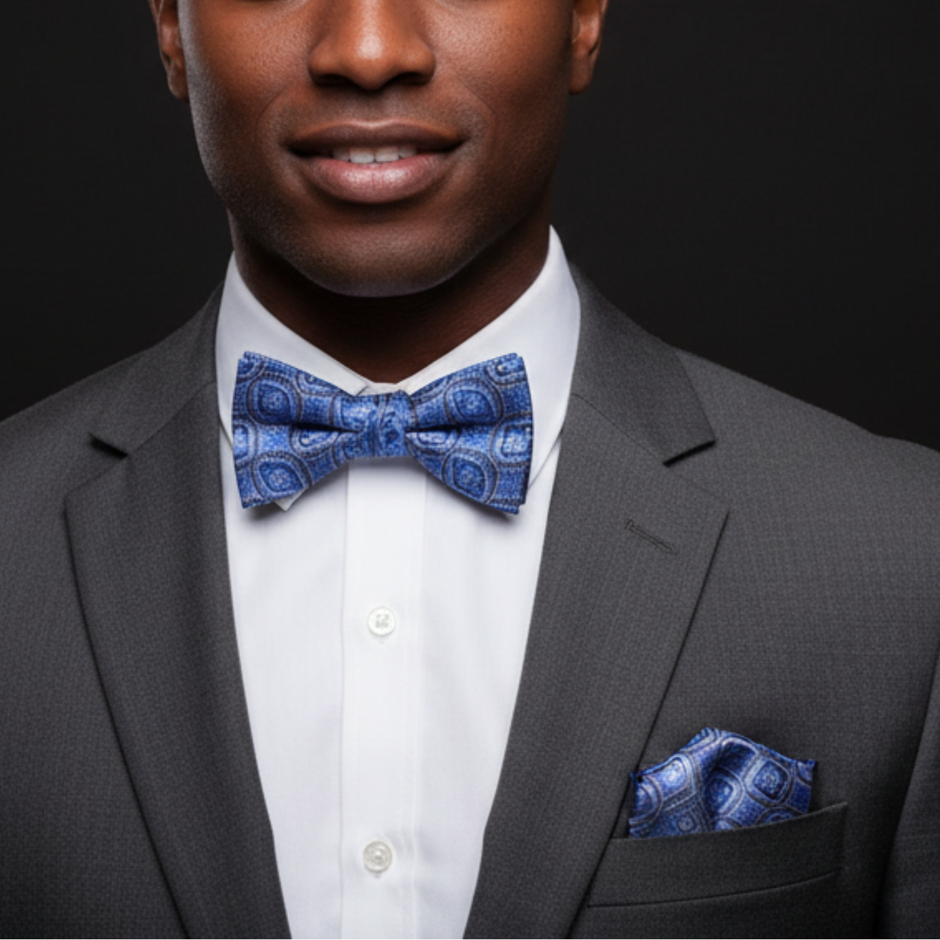 Man wearing a gray suit with a blue bow tie on a black background