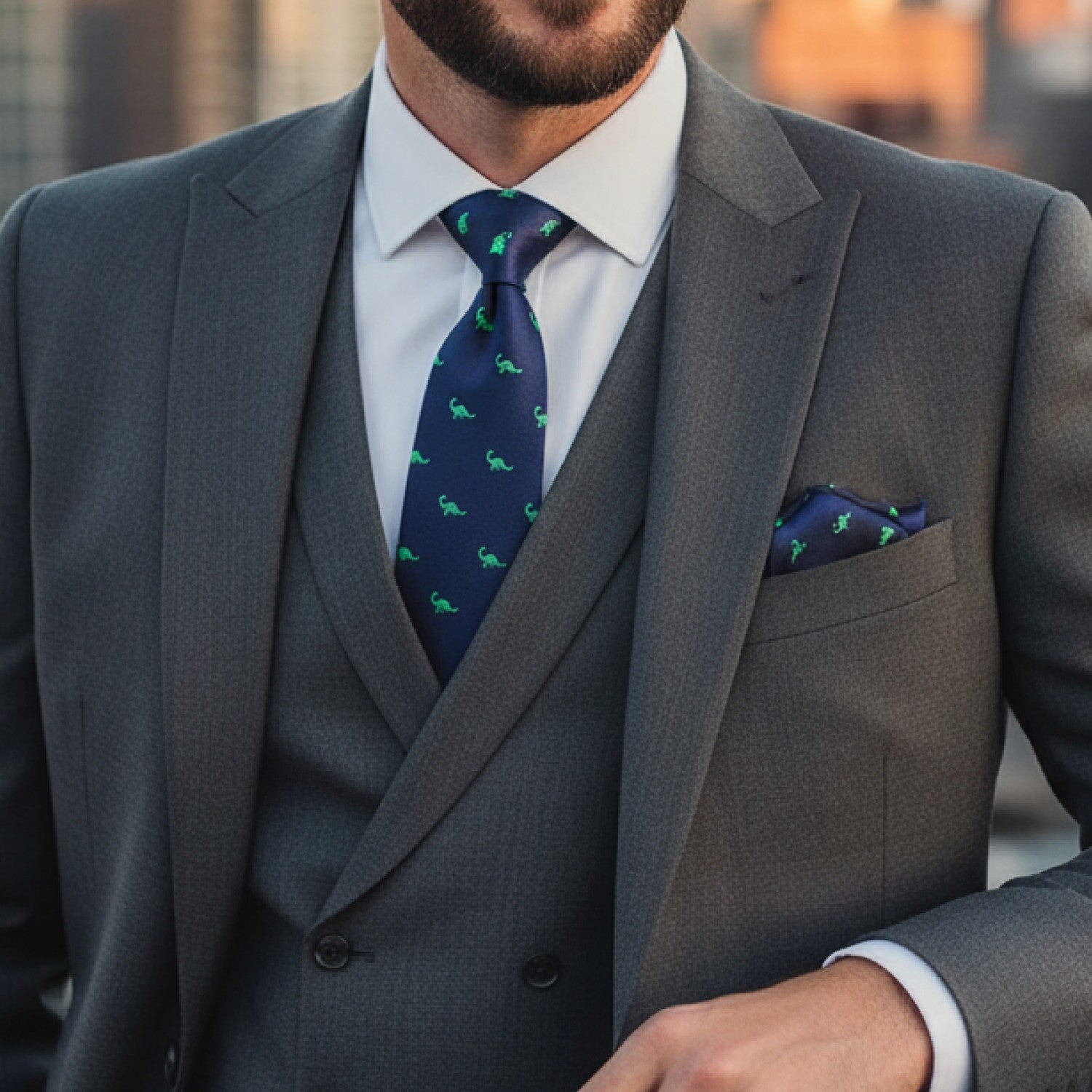 Man wearing a gray suit with a blue tie featuring green patterns.