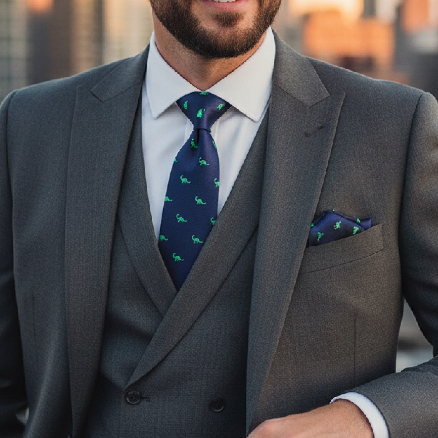 Man wearing a gray suit with a blue tie featuring green patterns.