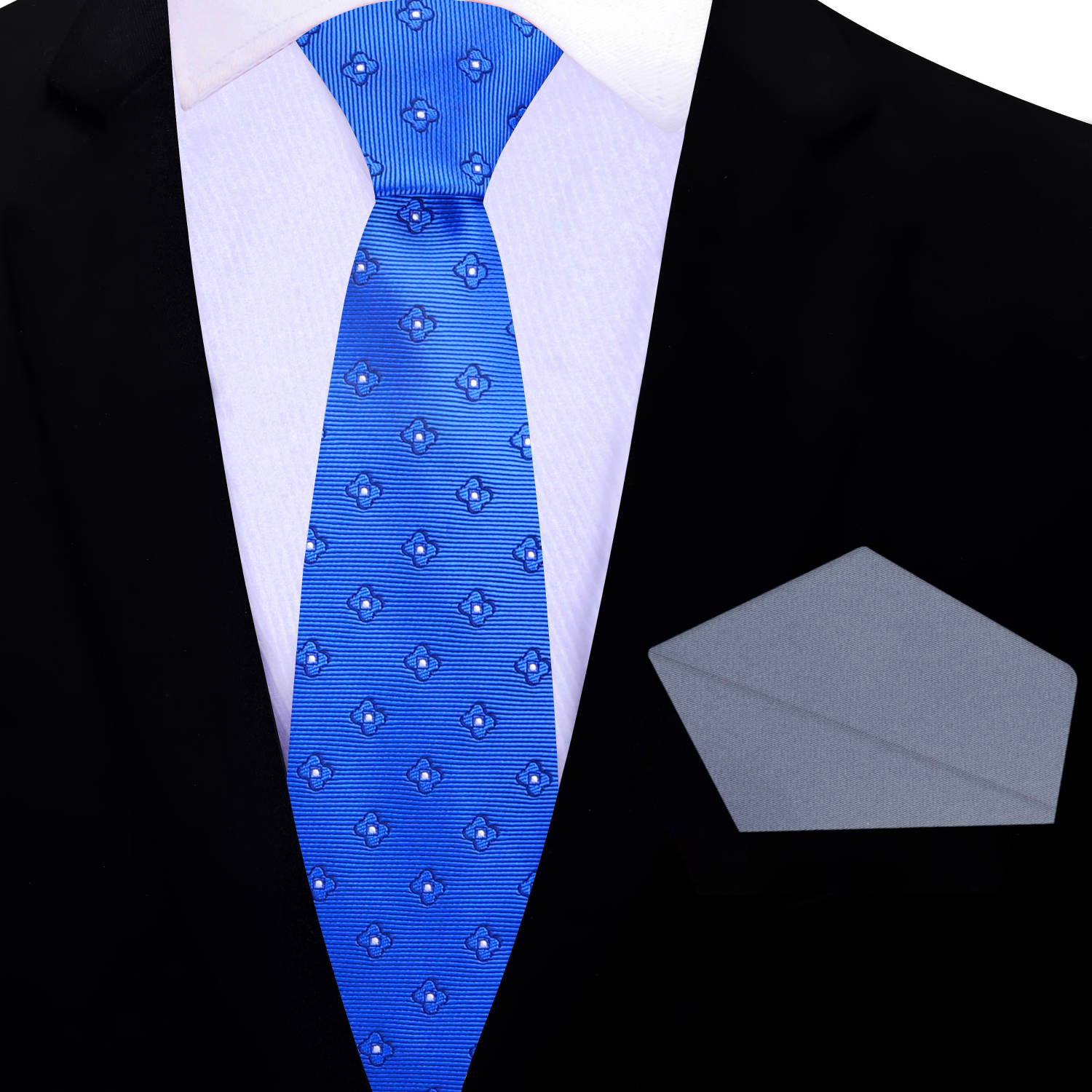 Blue small flowers patterned thin tie and grey pocket square on a black suit jacket.