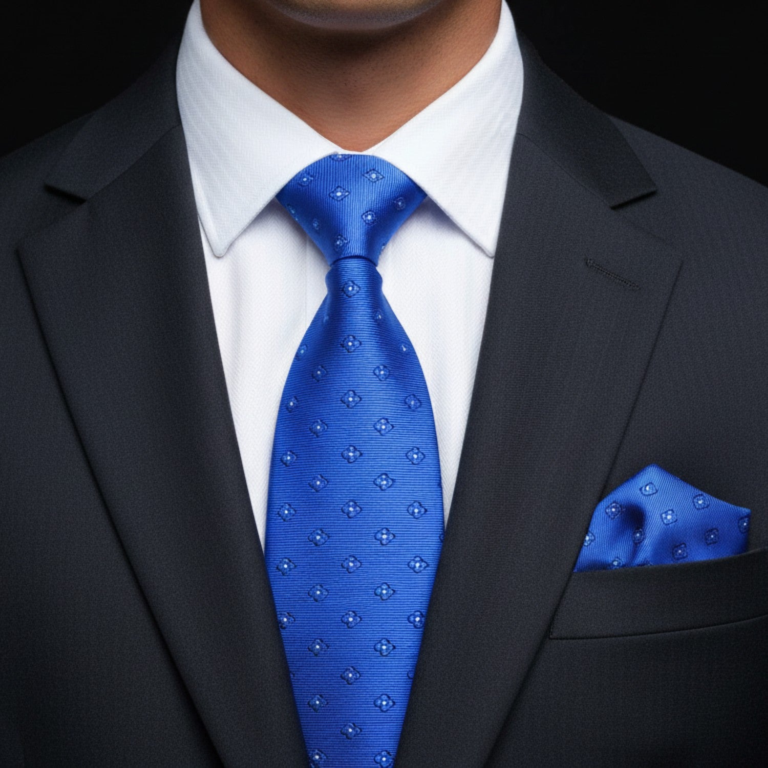 Man wearing a black suit with a blue tie and matching pocket square.