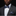 A close-up of a man wearing a dark gray suit jacket, white dress shirt, and a blue paisley patterned bow tie with a matching pocket square.