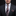 Man wearing a black suit with a blue brown and red paisley patterned tie and pocket square against a dark background