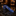 A blue patterned necktie with paisley and floral motifs, rolled and resting on a polished black marble countertop in a dimly lit retail environment.