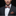 Man wearing a dark suit with a patterned bow tie and pocket square on a black background
