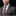Man wearing a gray suit with a brown tie and pocket square on a black background