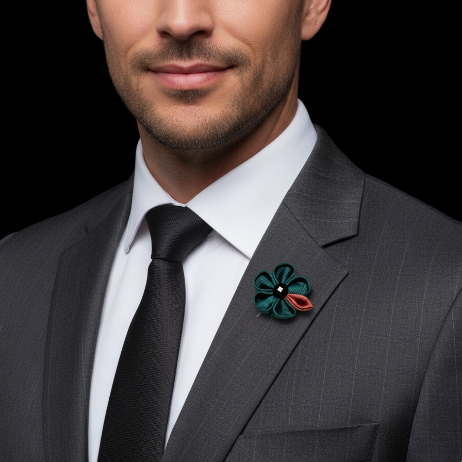 Man wearing a gray suit with a floral lapel pin on a black background