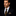 Man wearing a black suit with a patterned tie and pocket square on a dark background