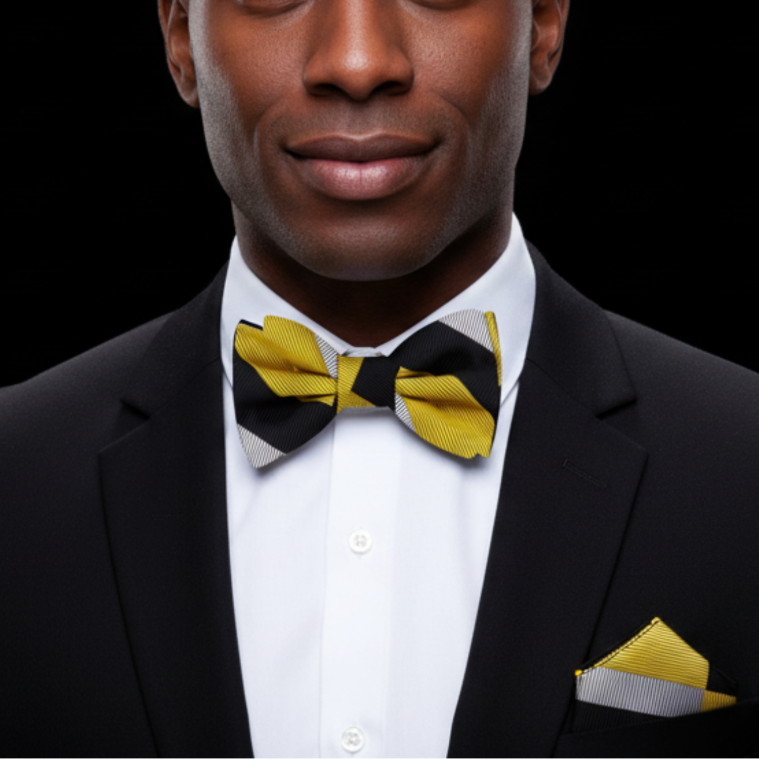 Man wearing a black suit with a yellow and black bow tie and matching pocket square.