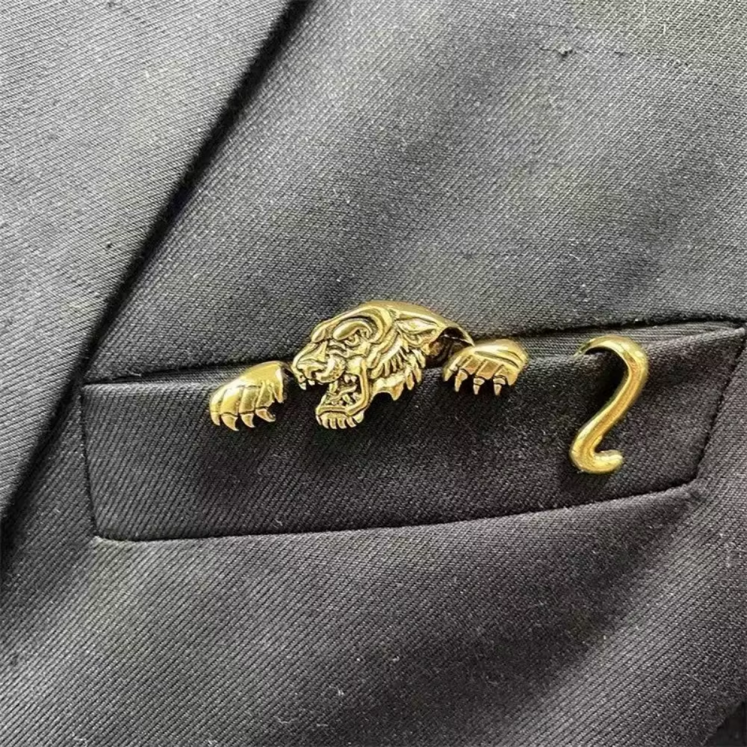 Gold tiger-shaped lapel pin on a gray suit jacket