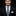 Man wearing a black suit with a colorful tie and white pocket square on a black background
