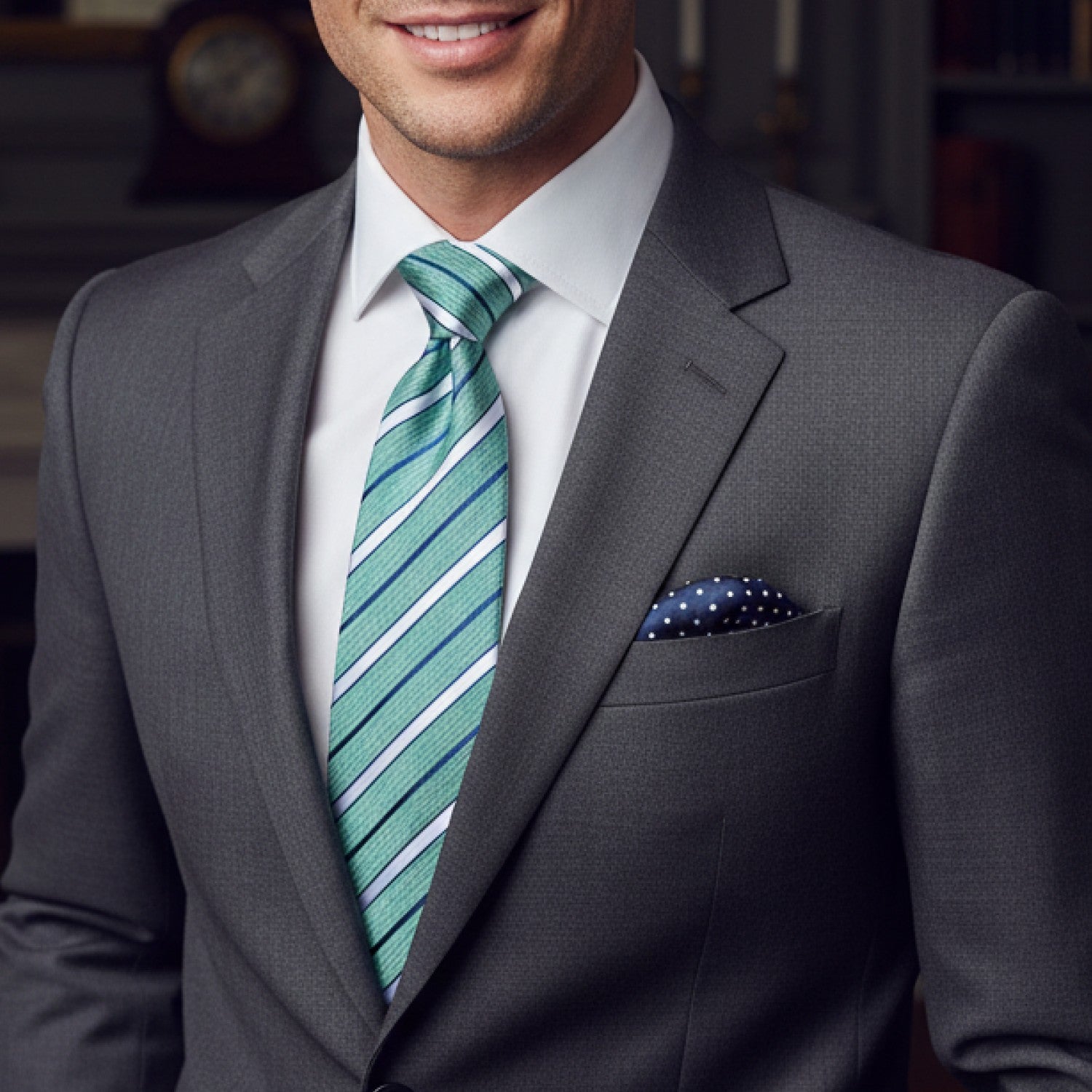 Man wearing a gray suit with a green striped tie and white shirt.