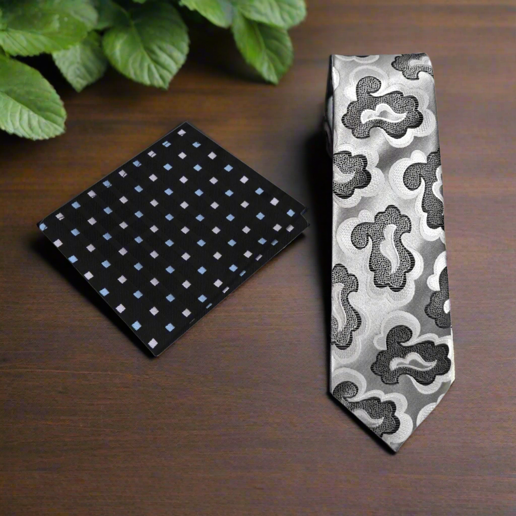 Black and blue patterned pocket square and gray and white patterned tie on a white background
