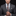 Man wearing a gray suit with a patterned tie and pocket square on a black background