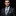 Man wearing a dark suit with a plaid tie and pocket square against a black background