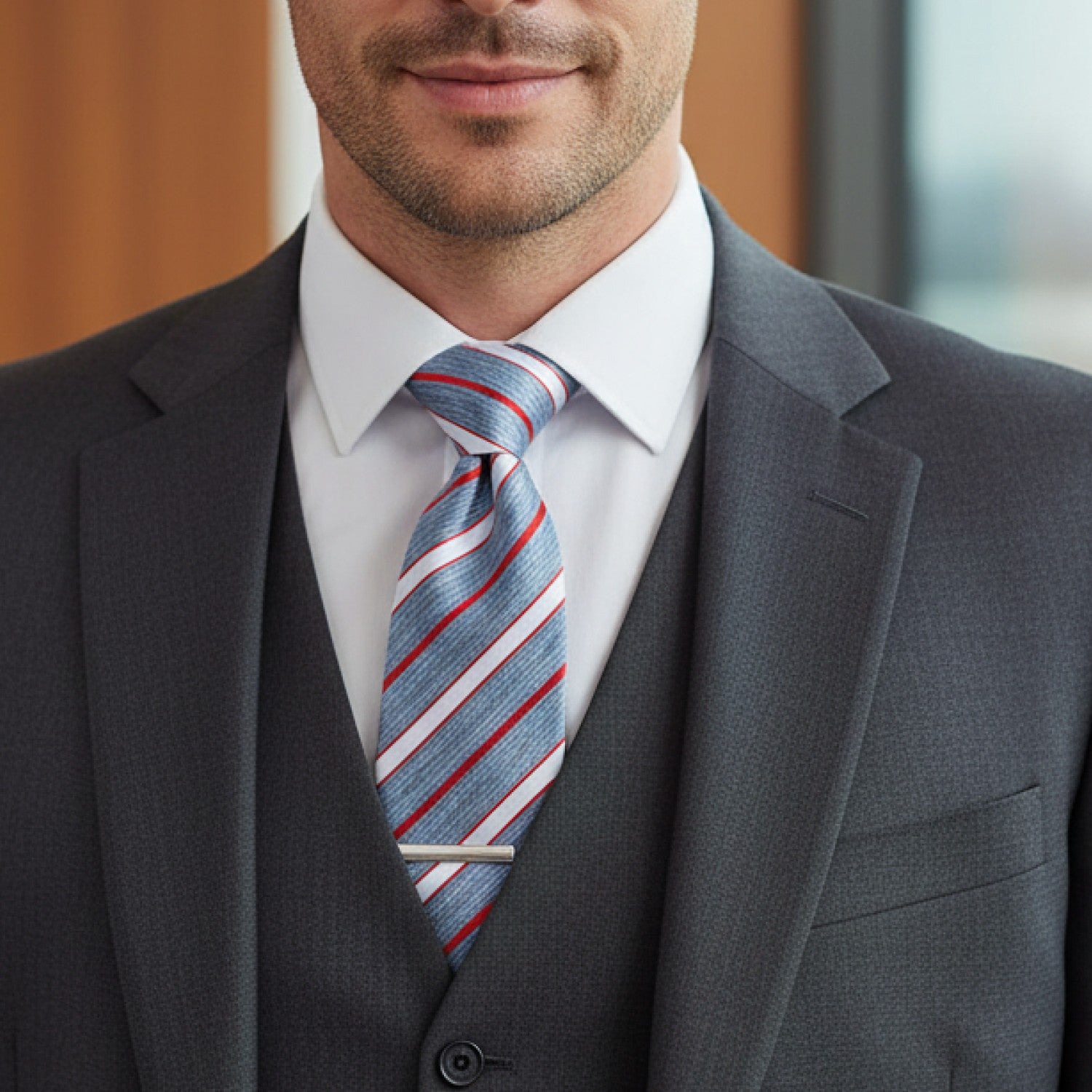 Man wearing a gray suit with a striped tie indoors