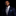 Man wearing a navy suit with a blue and yellow checkered tie and pocket square on a black background