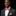 Man wearing a gray suit with an orange bow tie and pocket square on a black background