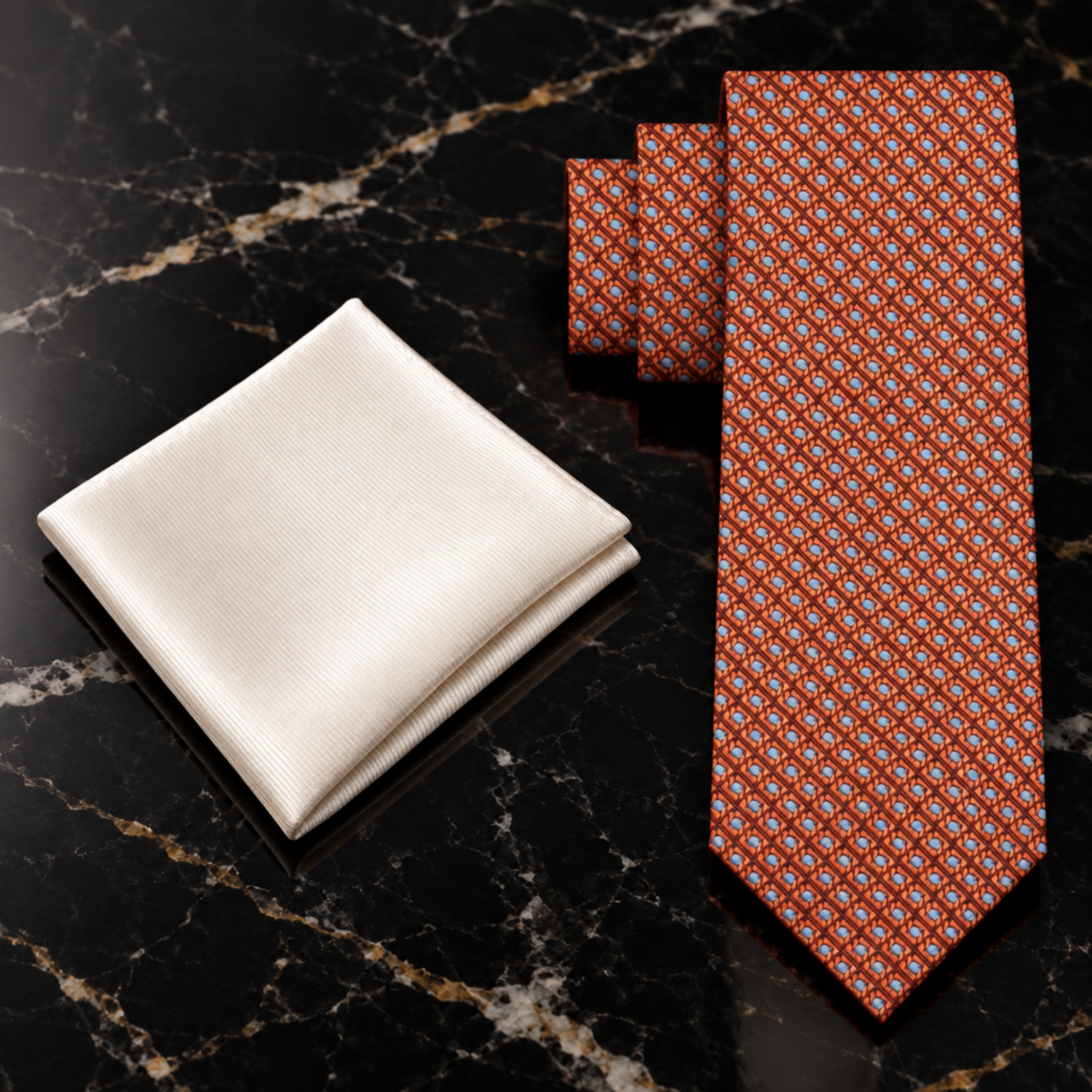 Black tie and white pocket square on a dark marble surface with decorative items.