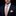 Man wearing a navy suit with an orange patterned tie and pocket square on a black background