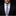Man wearing a black suit with a white shirt and a patterned blue tie against a dark background