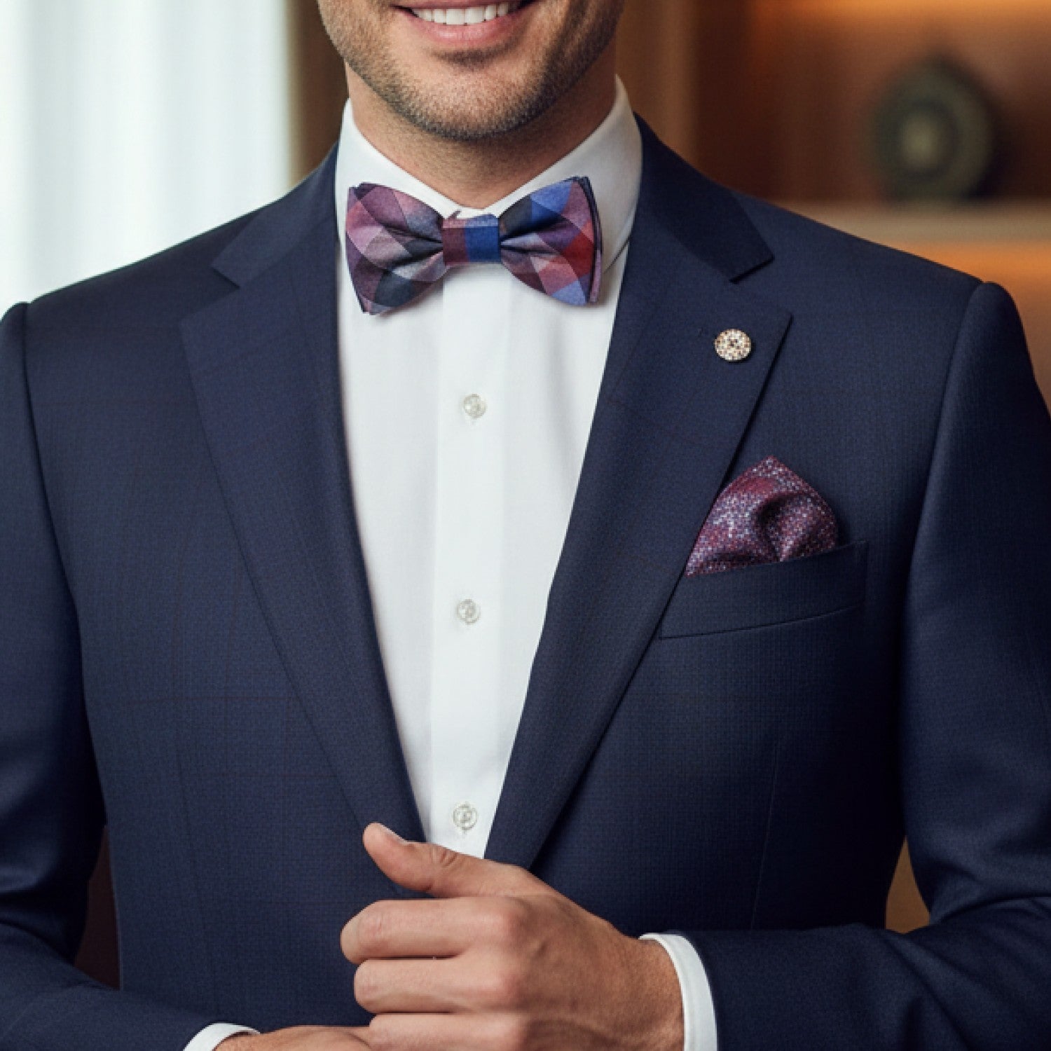 Man wearing a navy suit with a colorful bow tie and pocket square.