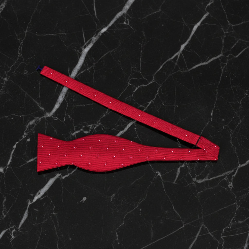 Red bow tie with white polka dots on a black marble background
