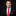 Man wearing a black suit with a red floral tie and pocket square on a black background