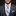 Man wearing a gray suit with a blue striped tie and pocket square on a black background