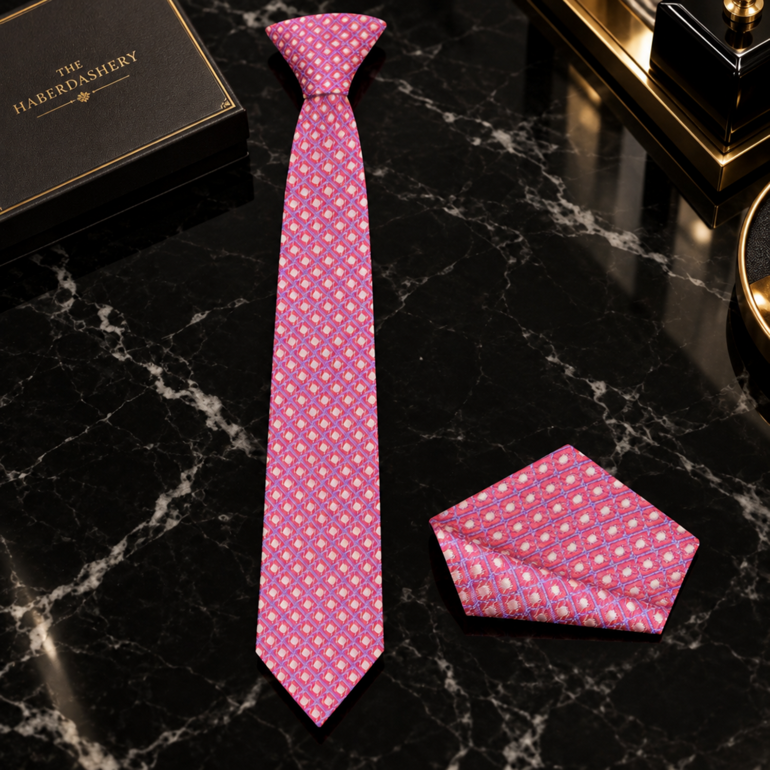 A pink patterned necktie and matching pocket square set, styled on a white dress shirt and black suit jacket.