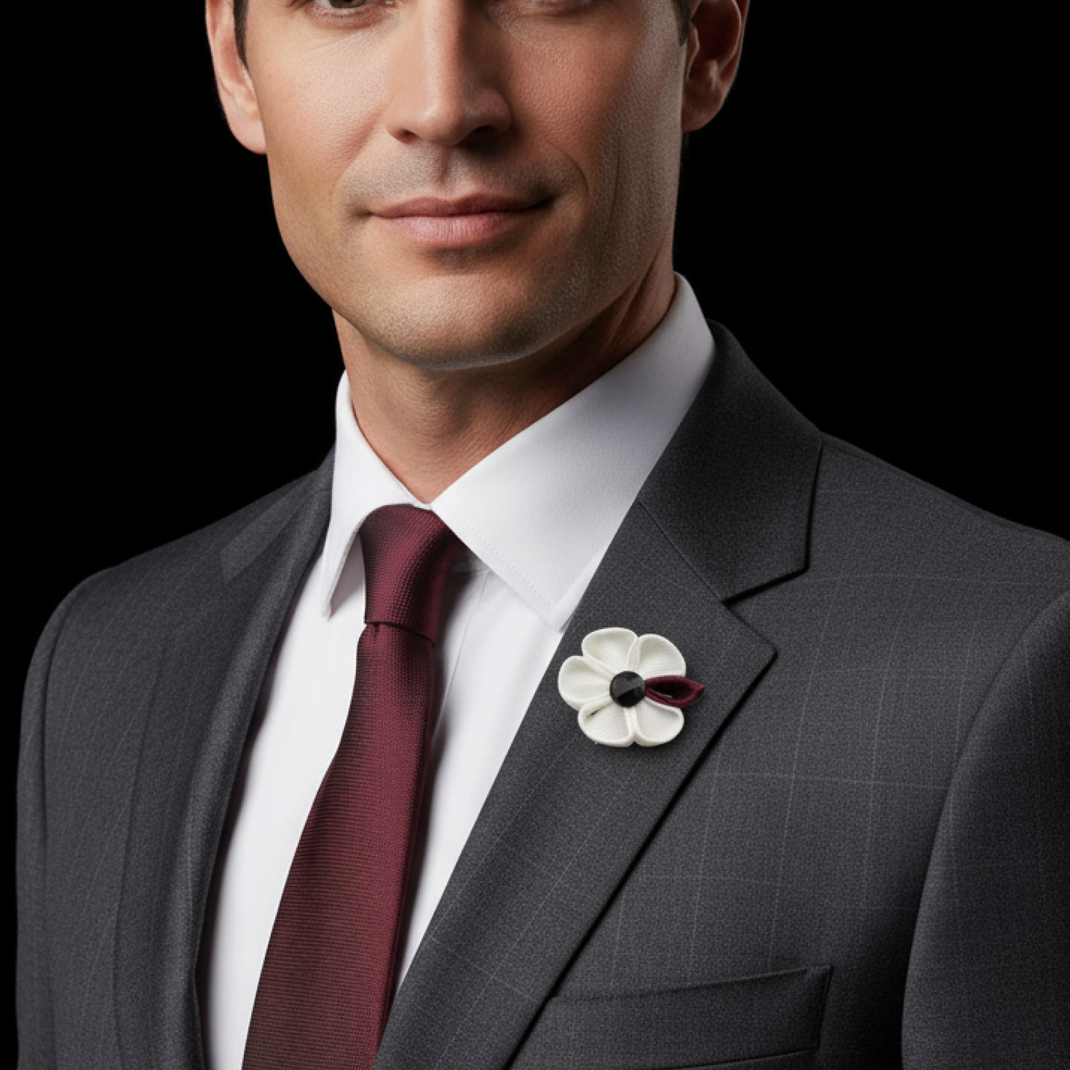 Man wearing a gray suit with a white flower lapel pin on a black background