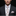 Man wearing a dark suit with a floral tie and pocket square against a black background