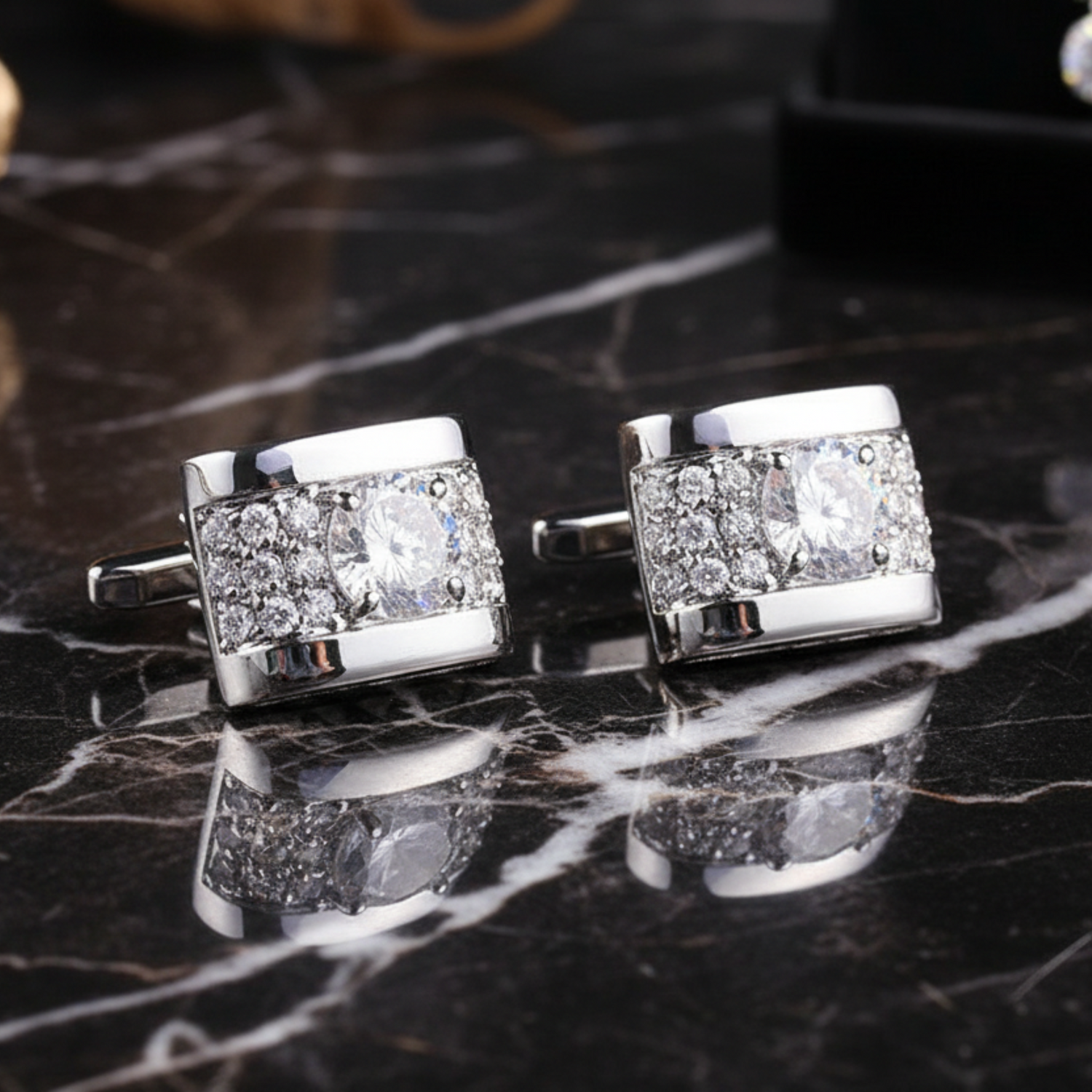 Silver cufflinks with gemstones on a dark marble surface