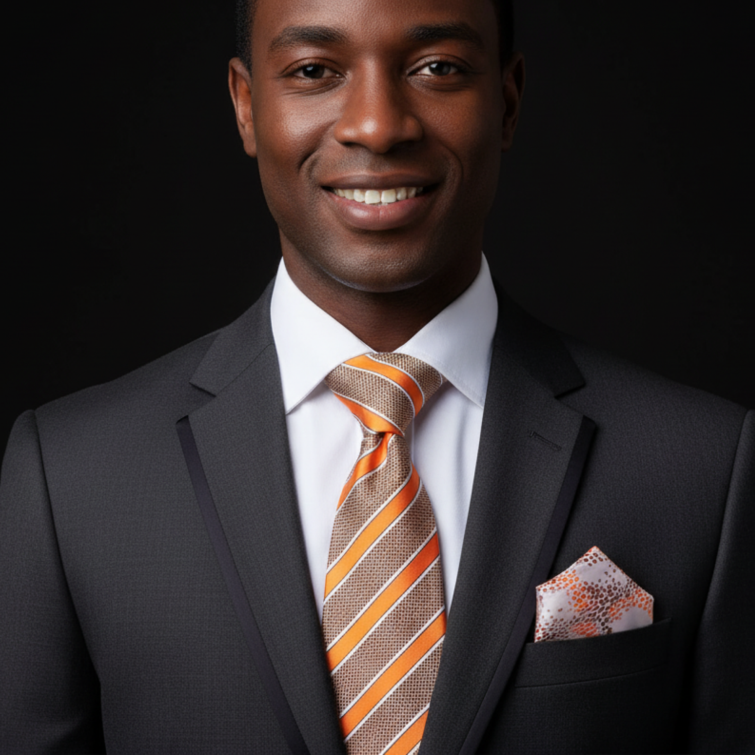 Man wearing a dark suit with an orange and brown striped tie and pocket square on a black background