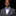 Man wearing a gray suit with a blue and white striped bow tie and pocket square on a black background